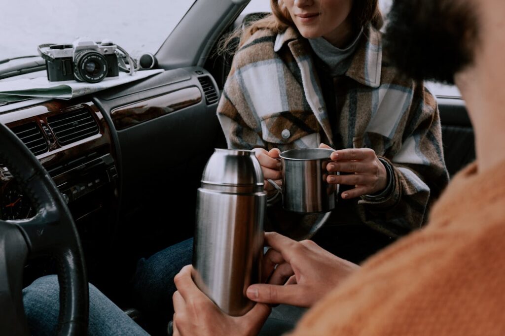 Mastering the First Impression: Your intriguing post title goes here A couple sits inside a car, holding a thermos and cups, enjoying a cozy moment.
