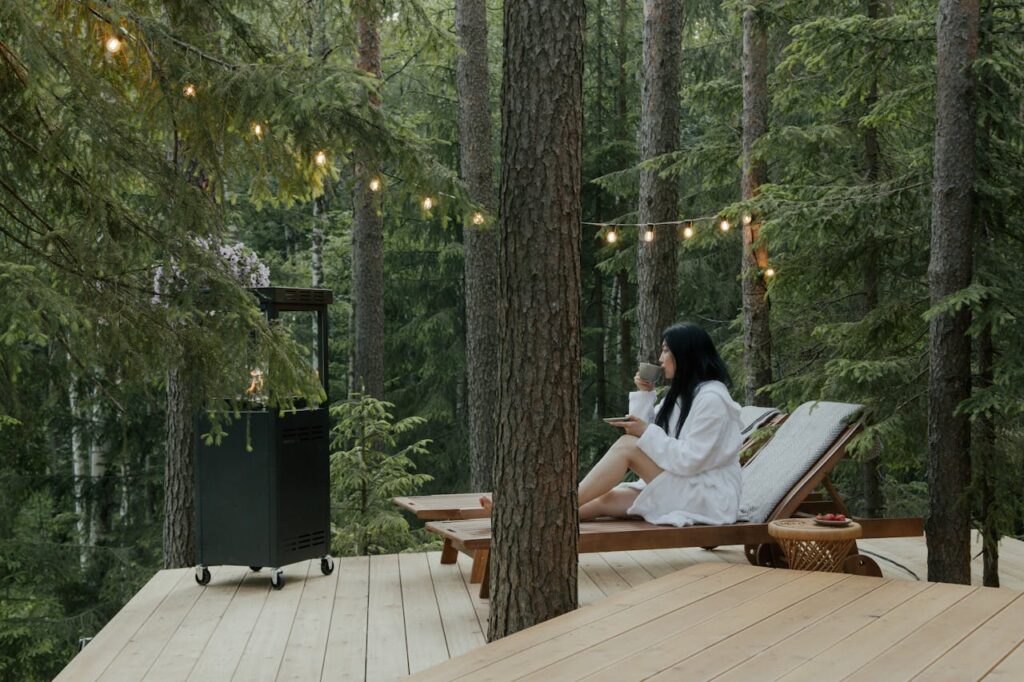 Crafting Captivating Headlines: Your awesome post title goes here Woman in bathrobe relaxing on a deck with drink, surrounded by forest tranquility.